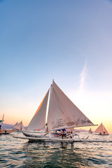 Boracay Island, Aklan, Philippines - Visitors enjoy sunset in a traditional Paraw boat powered by wind at Sunset. Circa January 2020