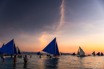 Boracay Island, Aklan, Philippines - Visitors enjoy sunset in a traditional Paraw boat powered by wind at Sunset. Circa January 2020