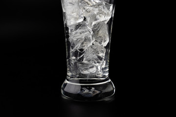 Glass with ice cubes on black background