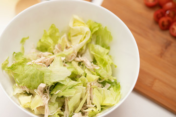 Caesar salad with chicken and iceberg leaves and small tomatoes.