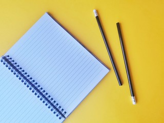 notebook, pen, on yellow background.  top view copy space