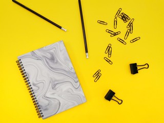 notebook, pen, on yellow background.  top view copy space
