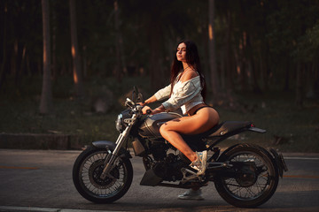 Plakat Sexy fit woman with a black motorcycle in cafe racer style