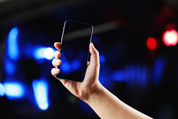 hand holding smart phone with bokeh background.