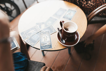 Woman is reading Tarot cards on the table in cafe