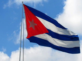 National flag of Cuba on flagpole in front of blue sky.