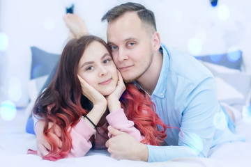 Young happy couple in love posing lying in bed with cute smiles Valentine's day Concept.