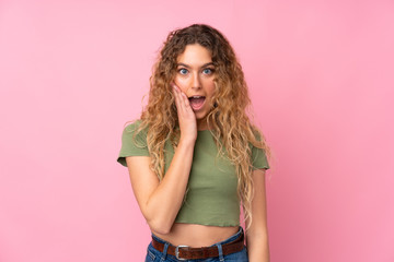 Young blonde woman with curly hair isolated on pink background with surprise and shocked facial expression