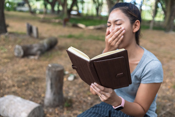 Fototapeta premium girl tired yawning sit park and read book.