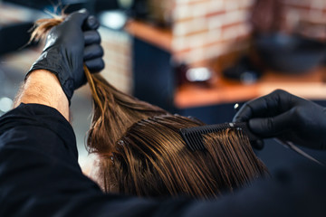 Close-up of hairdresser checking symmetry of haircut of his client at barbershop.