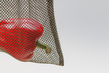 a fragment of a red bell paper in a green mesh reusable bag