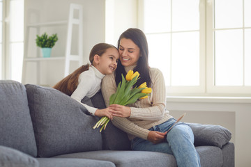 Happy mothers day. Daughter congratulates hugs his mother holds a bouquet of flowers in the room.