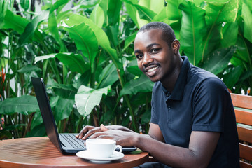 African man using a laptop computer outside a coffee cafe