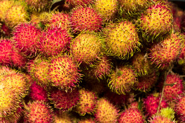 Close up, background of red and yellow rambutans, hairy round exotic tropical fruits.