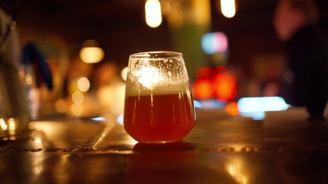 beer glass on table in bar. bartender on blurred background