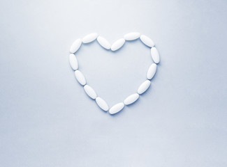 Heart shape made from pills for therapy, concept of treatment and health care on soft blue