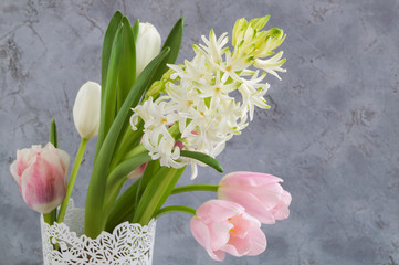 spring flowers in a white vase on a gray background.