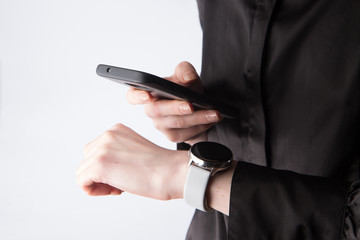 Person using smart watch on his wrist and holding smartphone in other hand