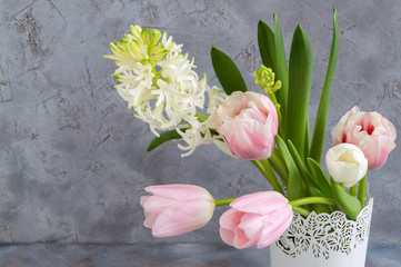 spring flowers in a white vase on a gray background.