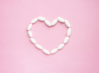 Heart shape made from pills for therapy, concept of treatment and health care on pink