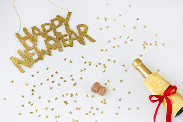 Festive background: confetti gold stars, the inscription Happy New Year and a bottle of champagne