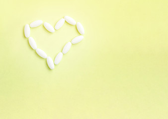Heart shape made from pills for therapy, concept of treatment and health care on yellow