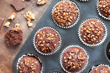 Chocolate cupcake in a paper mold.Cupcake with nuts and chocolate.Sweet pastries.Brown wooden background with scratches.
