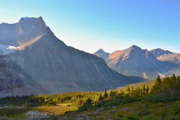 Panorama of Mount Edith Cavell. High mountains with glacier, sun rays illuminate the forest. Sunny day, blue sky, Canadian Rockies. 