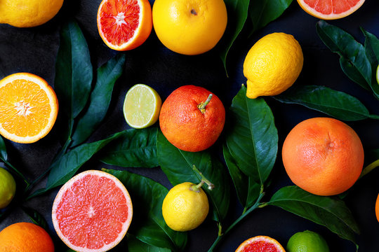 Bunte Zitrusfr&uuml;chte mit Orangen, Zitronen, Pink Grapefruit und Limetten auf schwarzem Schiefer Hintergrund