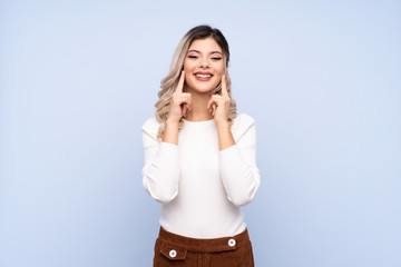 Young teenager girl over isolated blue background smiling with a happy and pleasant expression