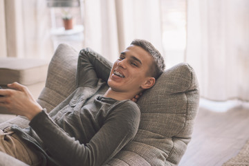 Obraz premium Handsome teenage guy relaxing on modern soft couch at home in living room