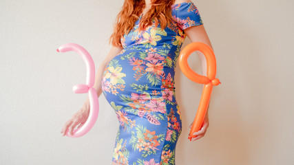 A close up photo of a pregnant young woman holding in her hands the week number thirty nine (39)...
