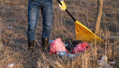 feet of a man and a rake - environmental protection (cleaning of packages, garbage)