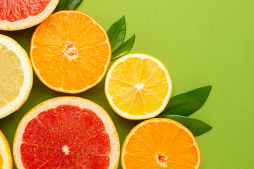Citruses fruits on green background , fruit flatlay, summer minimal compositon with grapefruit, lemon, mandarin and orange