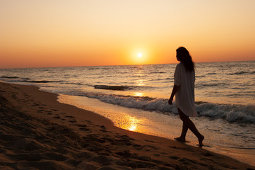 Girl walks along the coast at sunset, sunrise