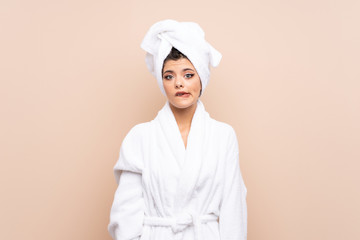 Teenager girl in a bathrobe over isolated background having doubts and with confuse face expression