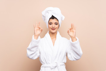 Teenager girl in a bathrobe over isolated background showing an ok sign with fingers