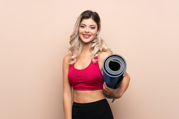 Teenager sport girl over isolated background with a mat and smiling