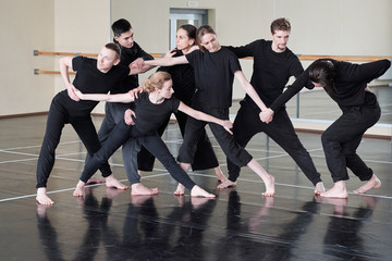 Group of professional contemporary dancers wearing black clothes having rehearsal in studio, horizontal shot