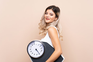 Teenager girl with weighing machine over isolated background with weighing machine