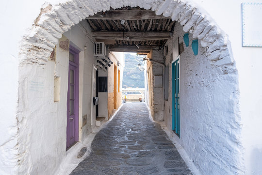 Fototapeta Traditional greek whitewashed buildings, cobblestone streets and stone structure arch. Ioulida village,Tzia, Kea island, Greece.