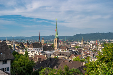 Fototapeta na wymiar Panoramic view of the roofs of Zurich city with towers and steeples, Switzerland. In the distance, the Swiss Alps are visible.