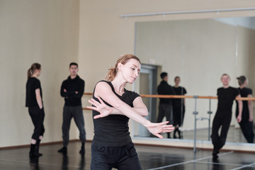 Fototapeta na wymiar Horizontal medium portrait of beautiful young woman wearing black clothes dancing in rehearsal studio