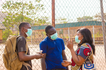 young black people wearing face masks having a conversation