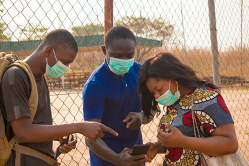 young black people wearing face masks having a conversation, checking something on a smartphone