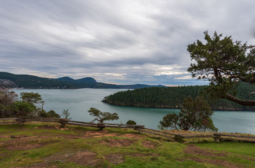 Wide angle landscape of hilltop with a few trees, ocean and forested island at Washington Park on Fidalgo Island