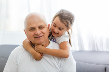 Portrait Of Grandfather With Granddaughter Relaxing Together On Sofa