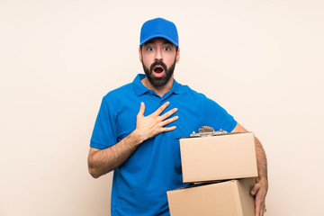 Delivery man with beard over isolated background surprised and shocked while looking right