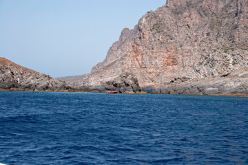 Some boats with tourists on board visit the rocky coast of the island of Marettimo, in the Egadi islands in Sicily, Italy.