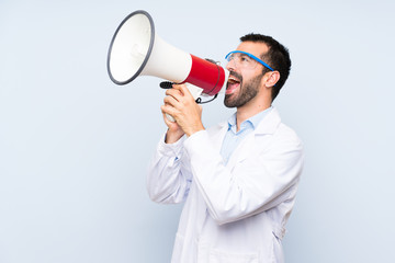 Young scientific holding laboratory flask over isolated background shouting through a megaphone